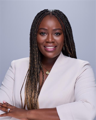 Professional woman with braided hair in a light blazer, smiling at the camera.